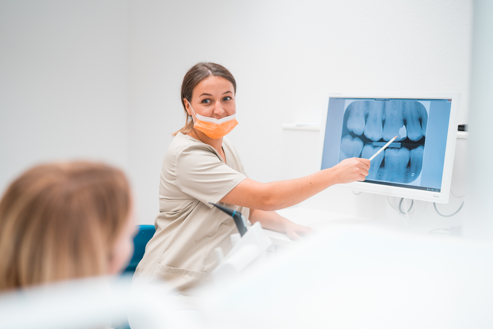 Zahnärztin zeigt auf einen Monitor für eine Patientin