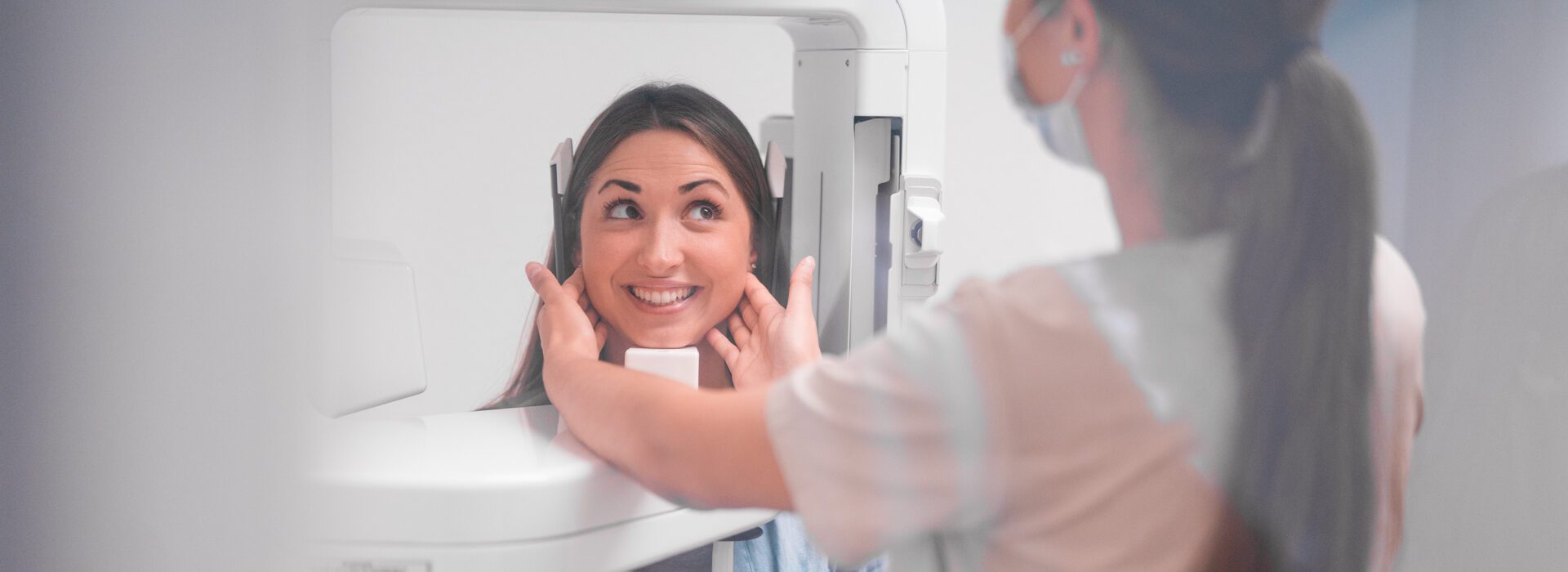 Mitarbeiterin kontrolliert die Veneers einer lächelnde Patientin nach erfolgreicher Behandlung durch die Zahnarztpraxis in Mönchengladbach