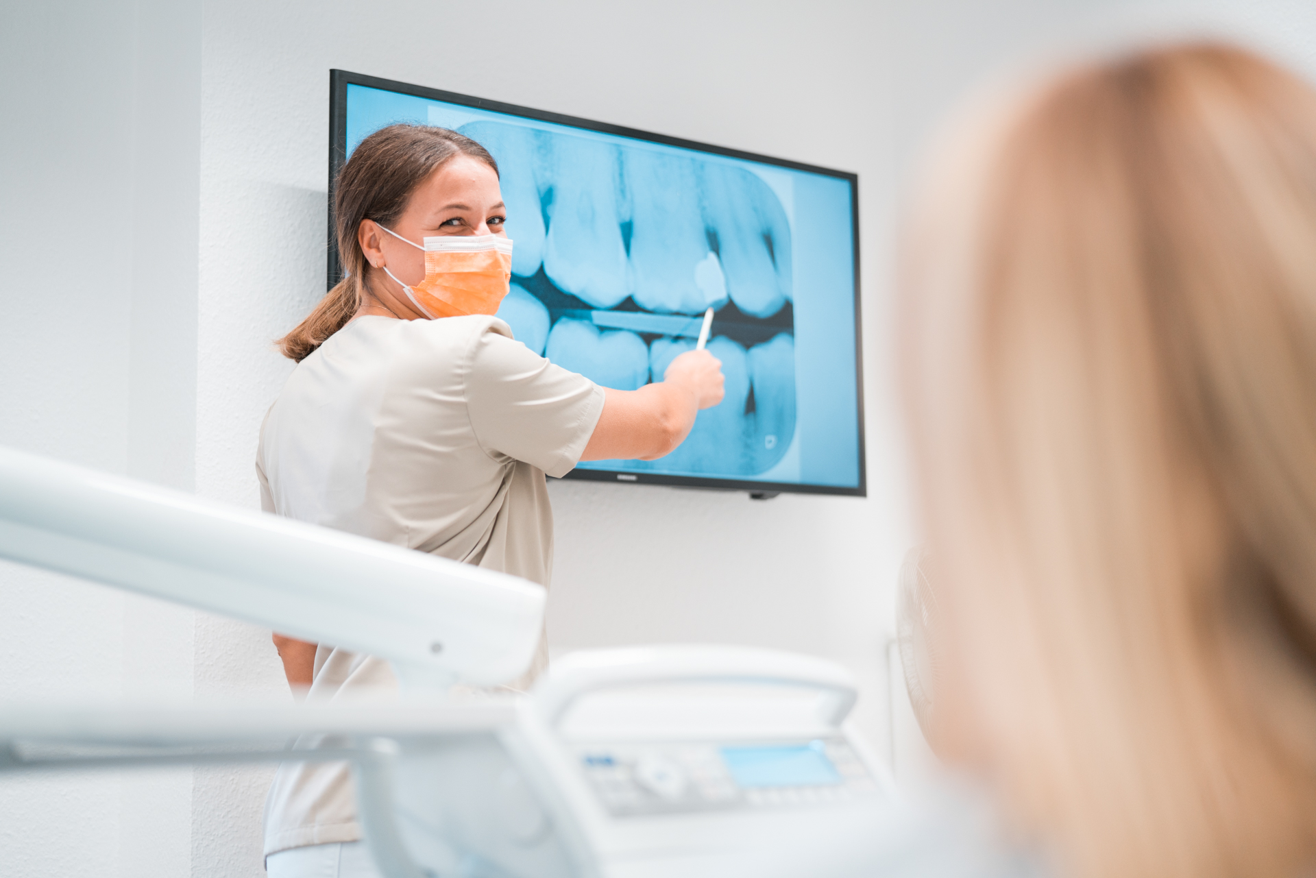 Zahnarzthelferin zeigt Zahnimplantat auf Bildschirm